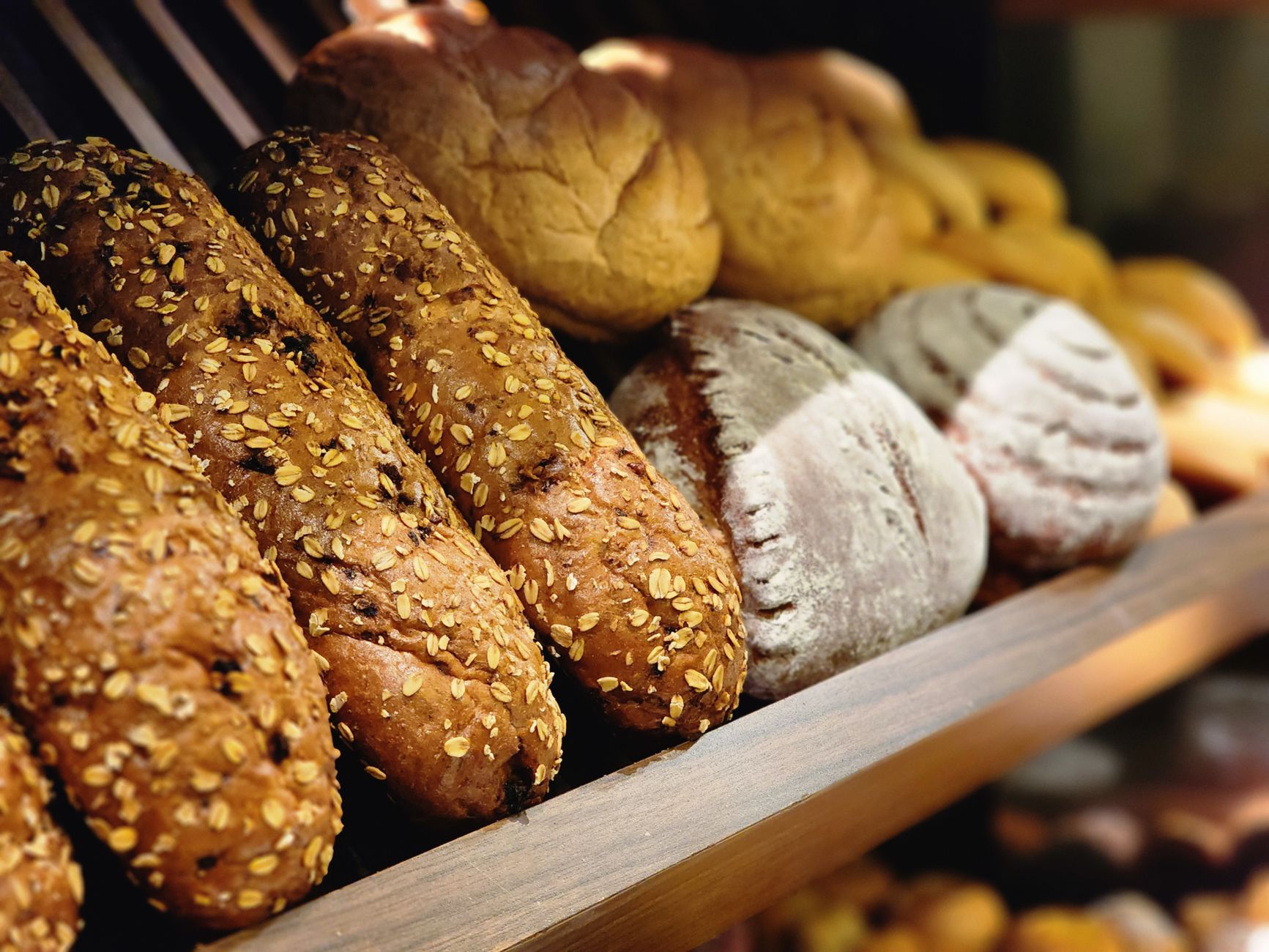 Imagem ilustrativa: Uma foto de close de pães artesanais variados e recém-assados em uma vitrine de padaria.