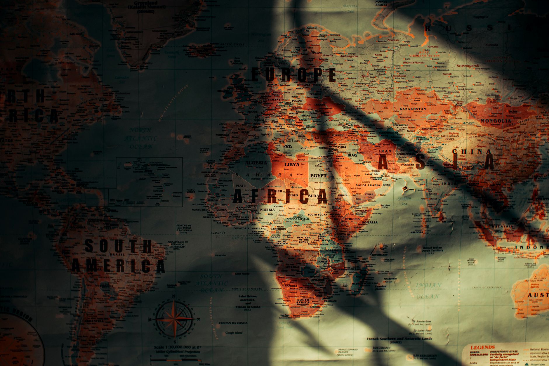 Imagem ilustrativa: Um mapa-múndi de estilo vintage apresentando continentes com sombras e luzes dramáticas que adicionam profundidade e mistério.
