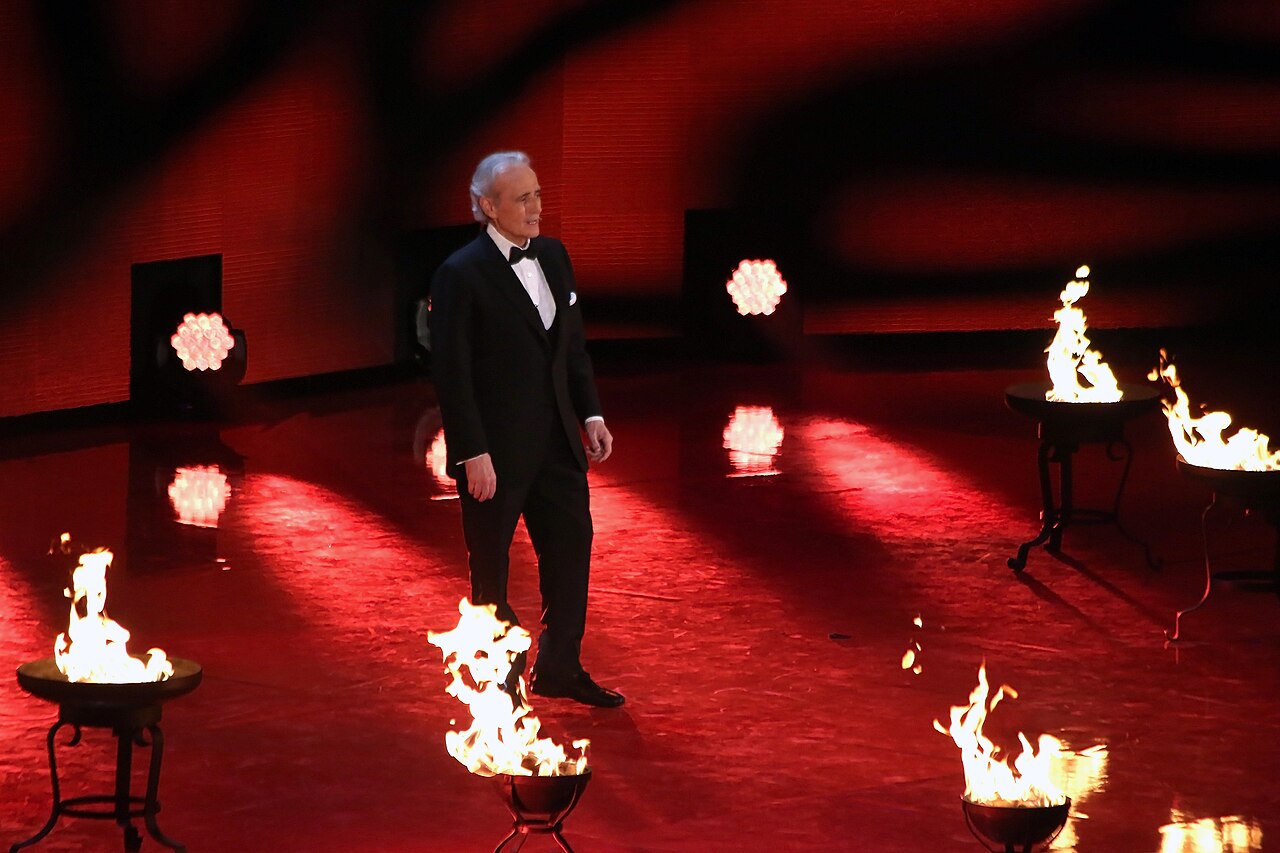 Imagem ilustrativa: O tenor José Carreras de smoking, sozinho num palco iluminado, durante apresentação
