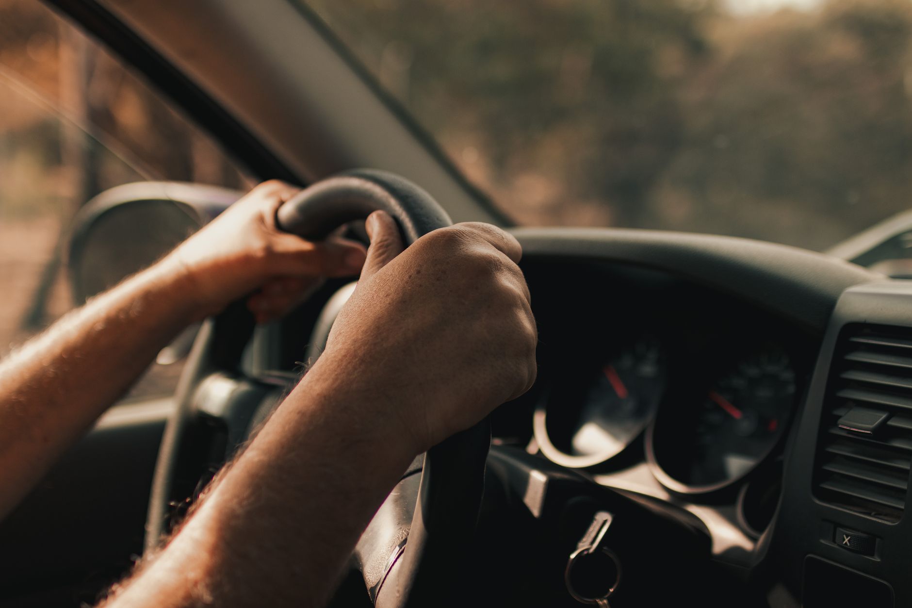 Imagem ilustrativa: Mãos do motorista no volante dentro de um veículo, focando no ato de dirigir.