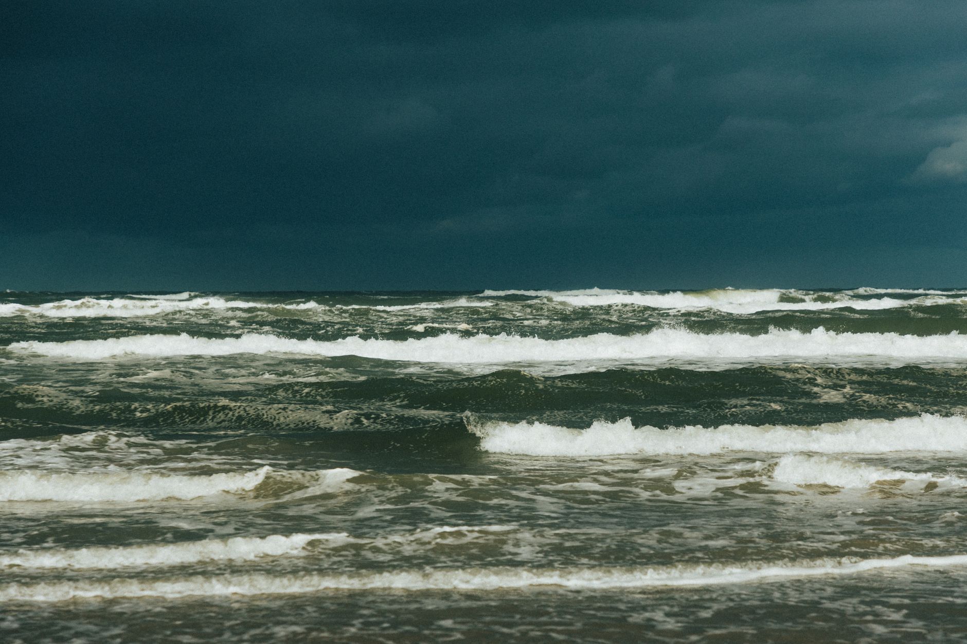 Imagem ilustrativa: Mar agitado, com ondas quebrando sob céu escuro e carregado