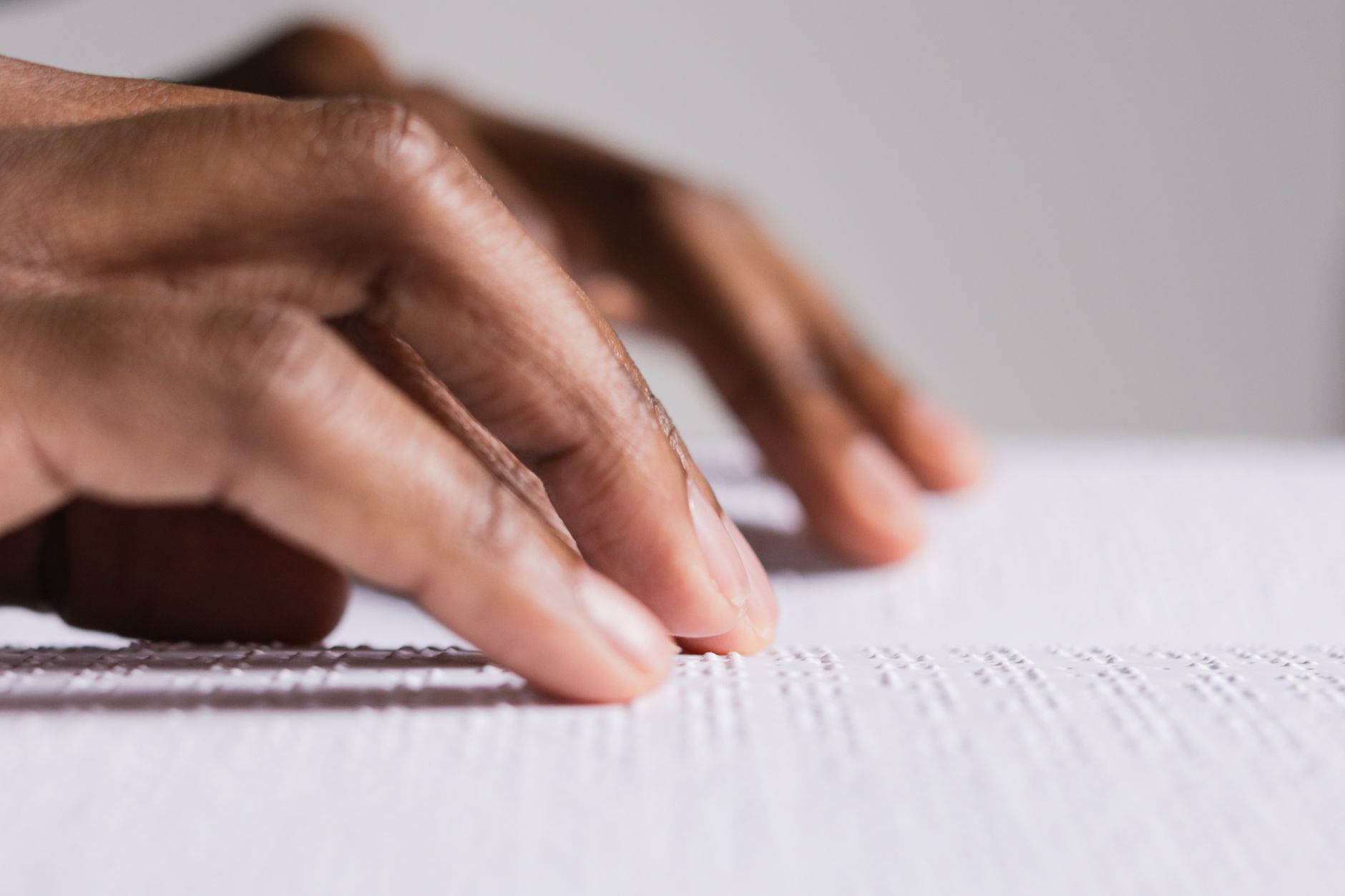 Imagem ilustrativa: Mãos tocando e lendo texto em Braille, destacando o aprendizado tátil e a acessibilidade.