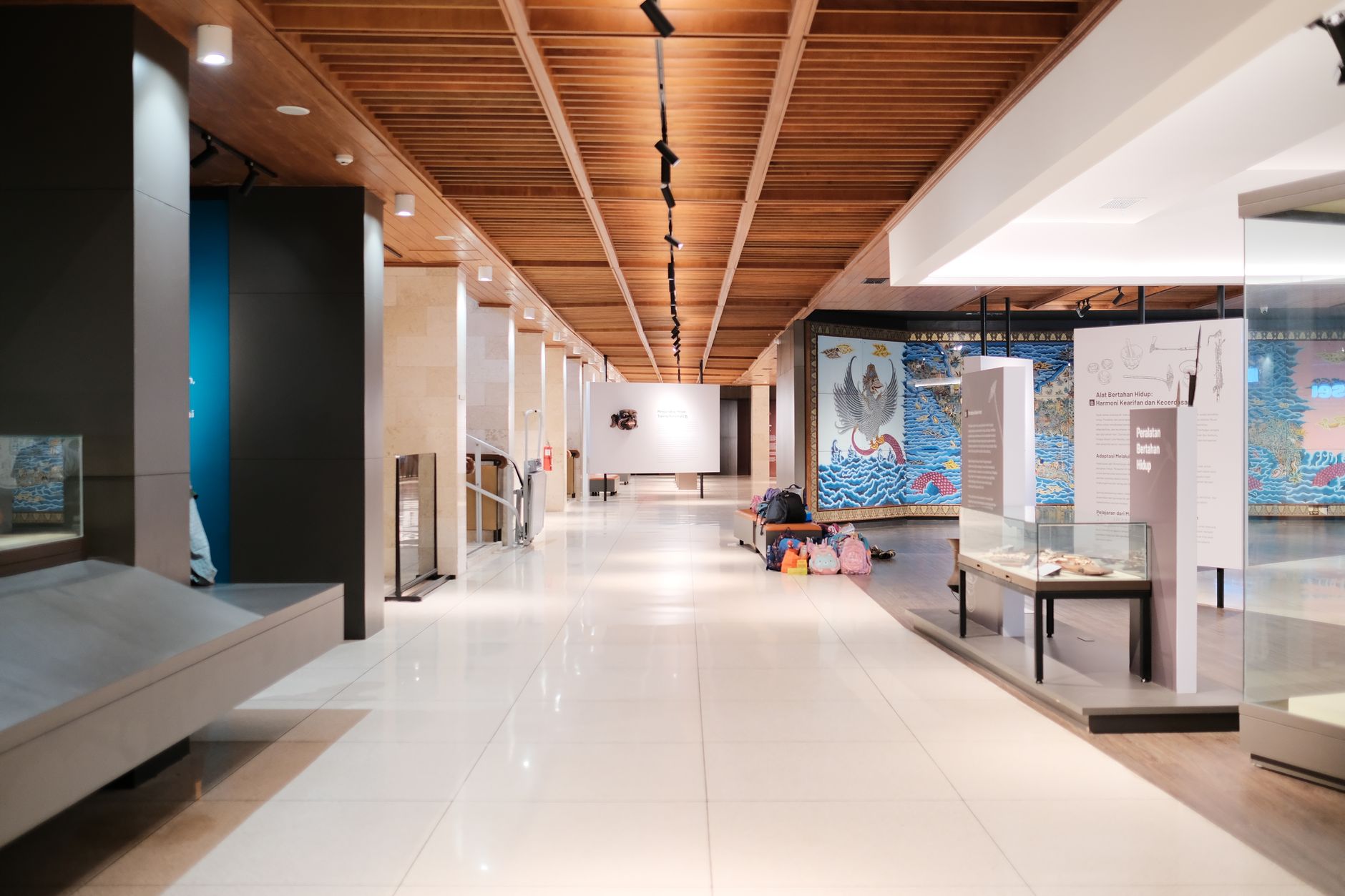 Imagem ilustrativa: Corredor iluminado de museu com exposições e passagens vazias, apresentando design moderno.