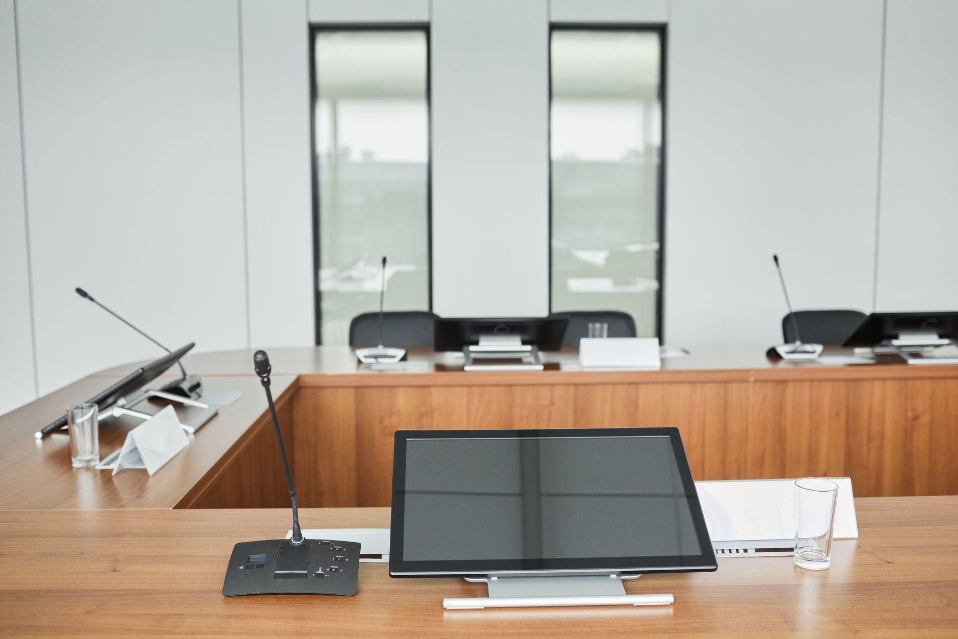 Imagem ilustrativa: Sala de sessões vazia, com microfones de mesa e bancadas de madeira.