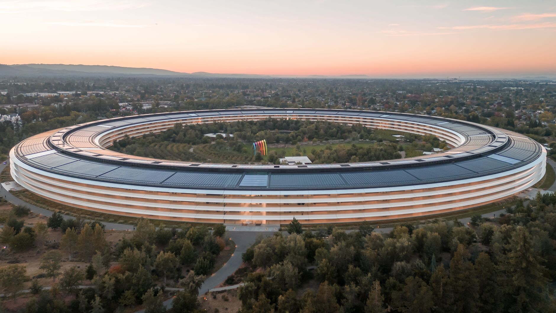 Imagem ilustrativa: Deslumbrante vista aérea do Apple Park em Cupertino ao amanhecer, destacando sua arquitetura futurista.