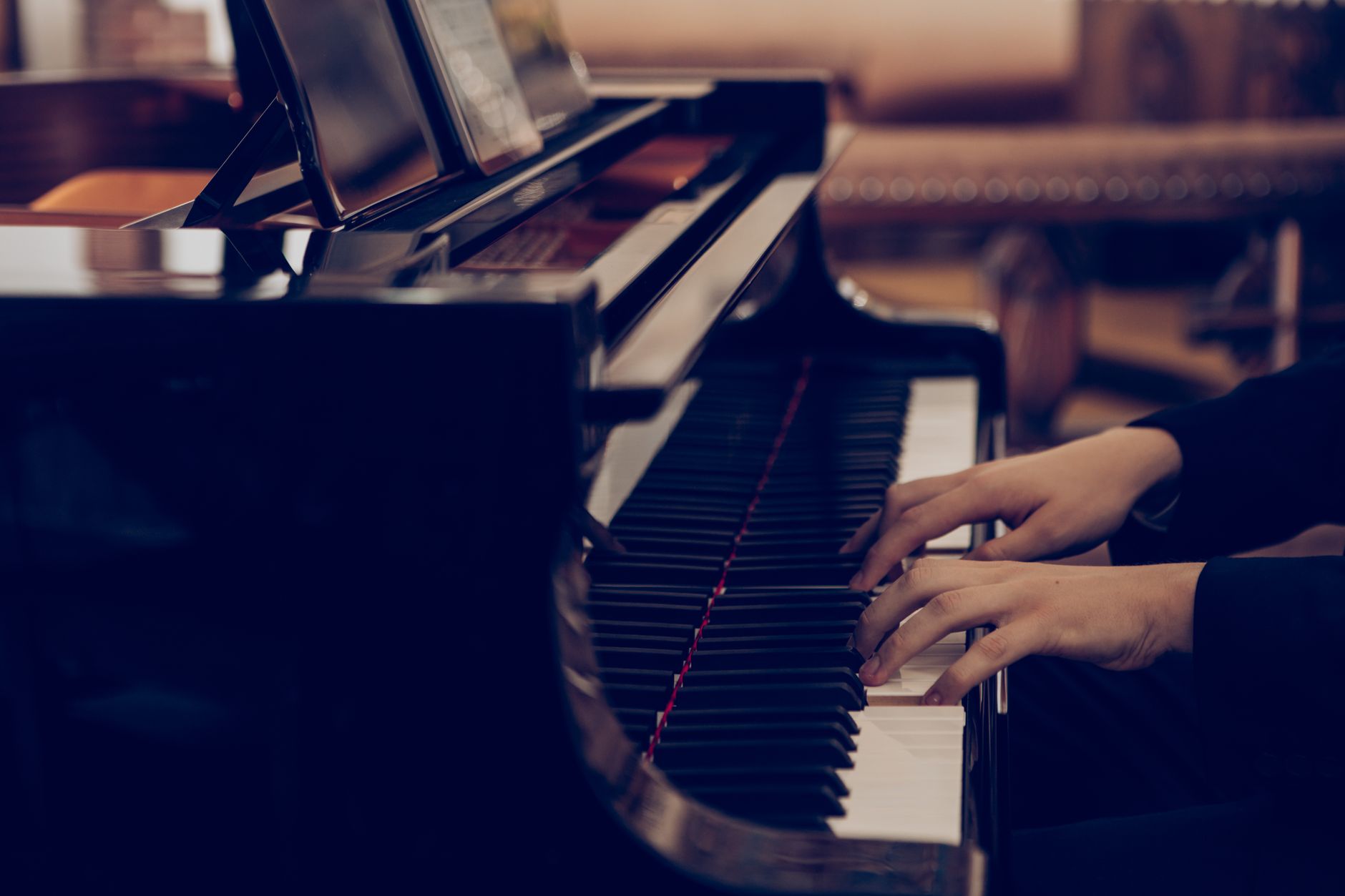 Imagem ilustrativa: Close-up de mãos tocando um piano de cauda, destacando elegância e habilidade.
