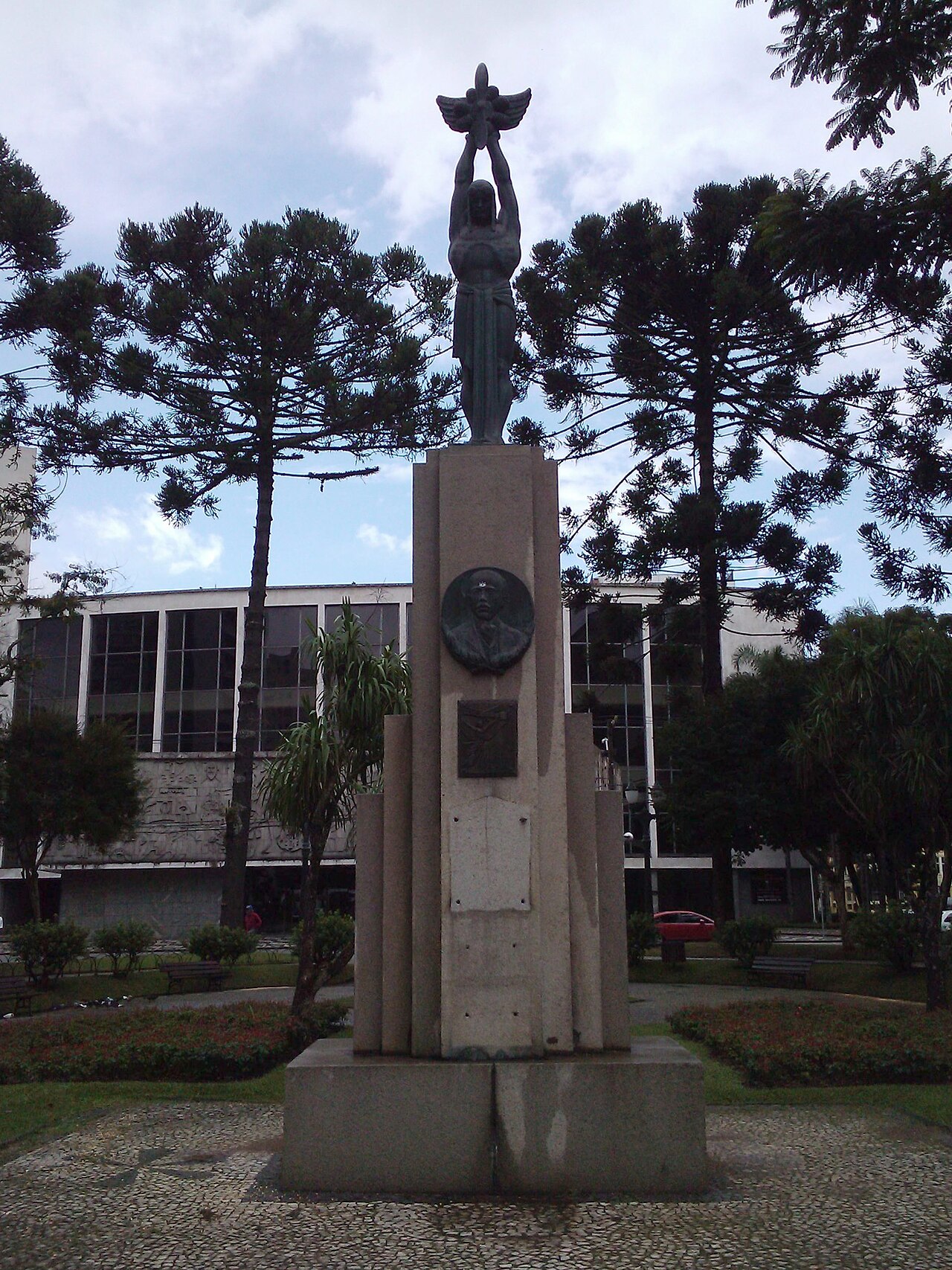 Imagem ilustrativa: Monumento na Praça Santos Andrade, em Curitiba, com o prédio do Teatro Guaíra ao fundo.