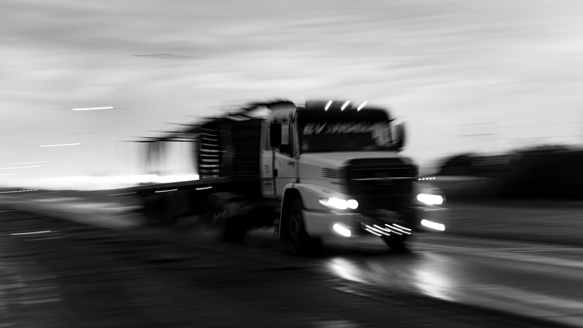 Imagem ilustrativa: Caminhão em movimento numa rodovia, em imagem de longa exposição, em preto e branco.