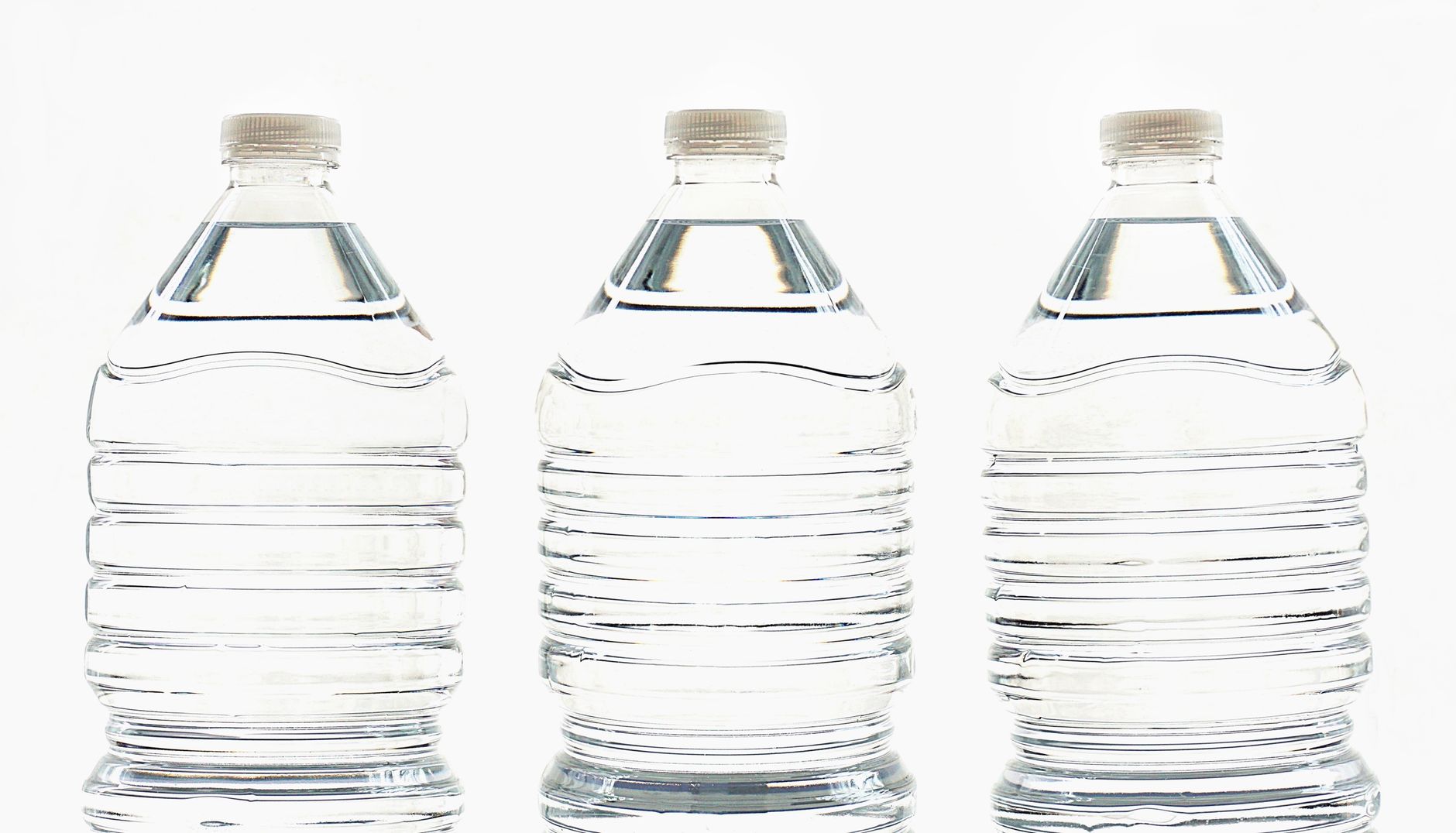 Imagem ilustrativa: Três garrafas plásticas transparentes preenchidas com água, alinhadas lado a lado.