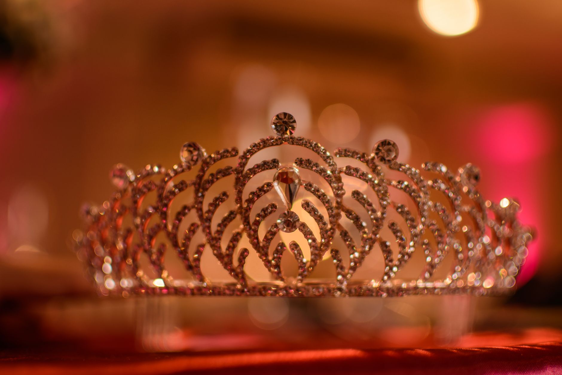 Imagem ilustrativa: Uma coroa de cristal lindamente detalhada brilhando sob uma iluminação suave e quente em um ambiente elegante.