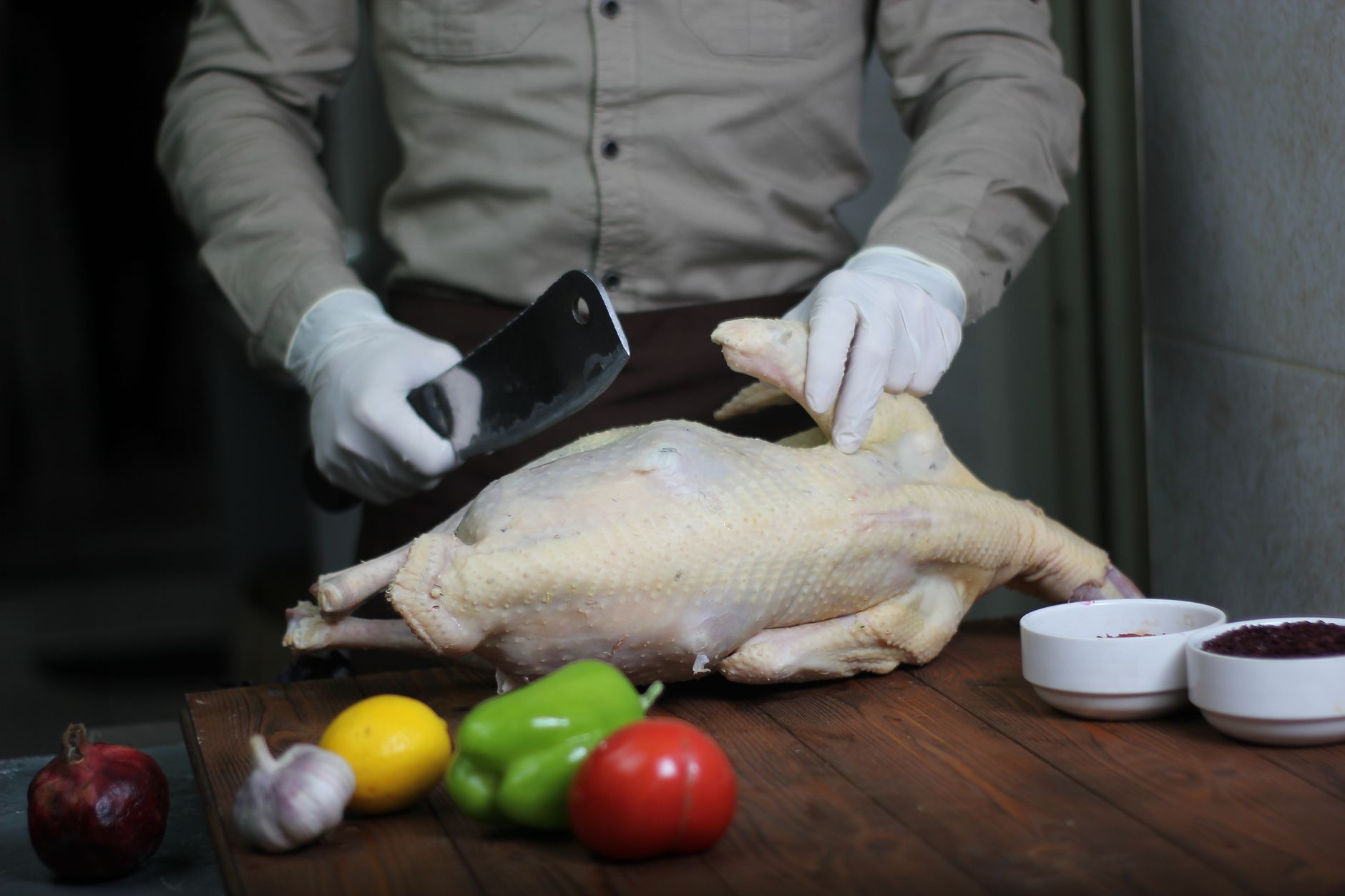 Imagem ilustrativa: Um chef preparando um frango cru para cozinhar, rodeado por ingredientes frescos como alho, limão e pimentões.