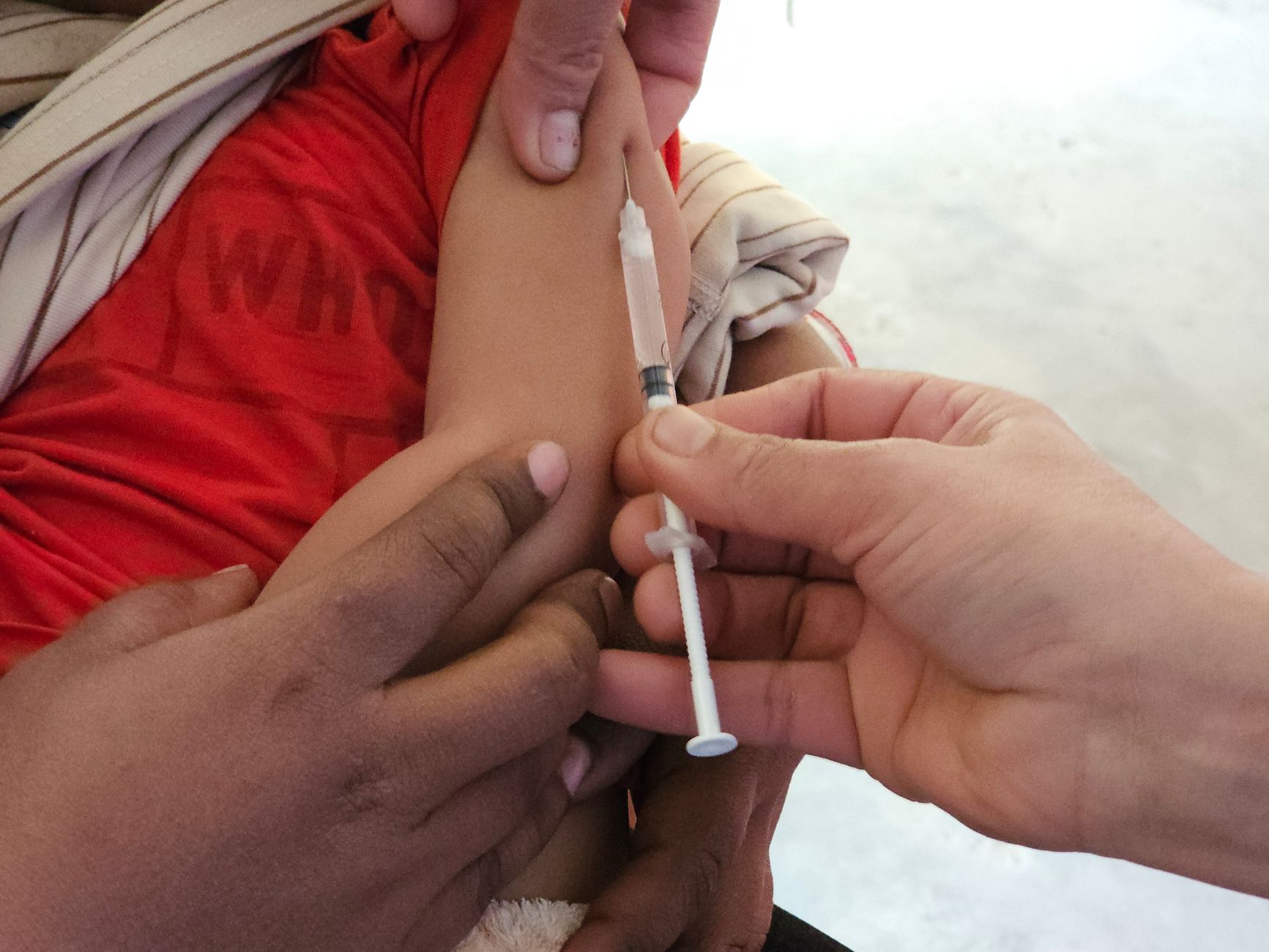 Imagem ilustrativa: Criança recebendo dose de vacina no braço, aplicada por profissional de saúde