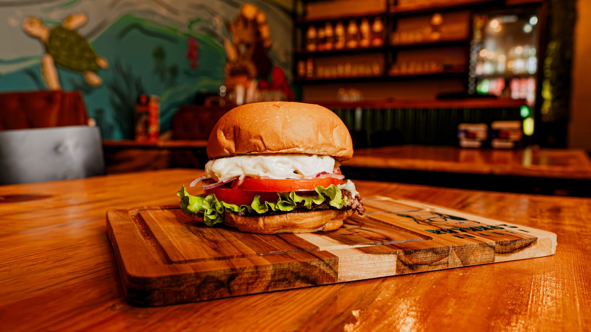 Imagem ilustrativa: Cheeseburger com coberturas frescas servido em um ambiente acolhedor de lanchonete.