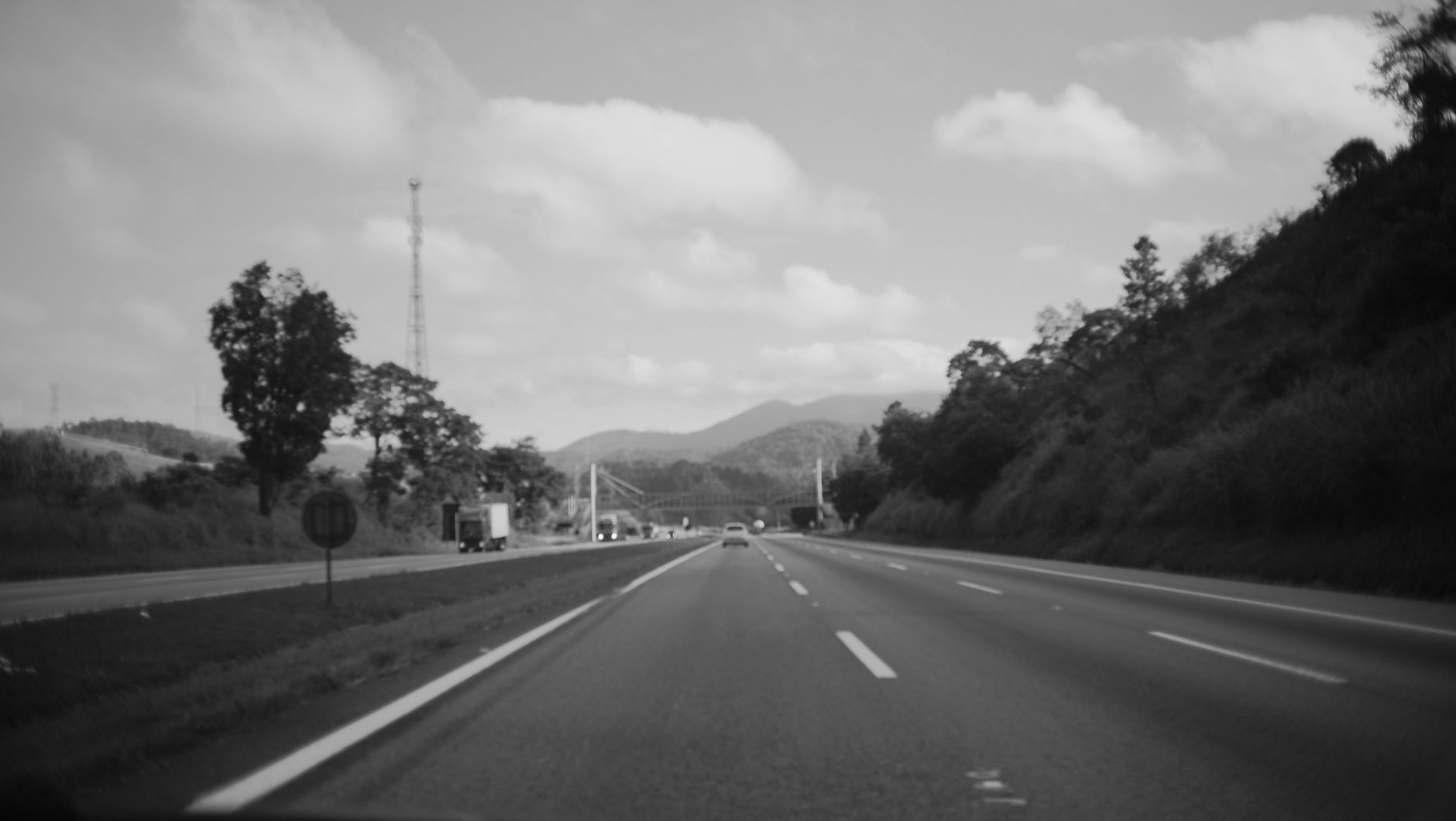 Imagem ilustrativa: Rodovia de pista dupla com faixas de sinalização, sob céu nublado.