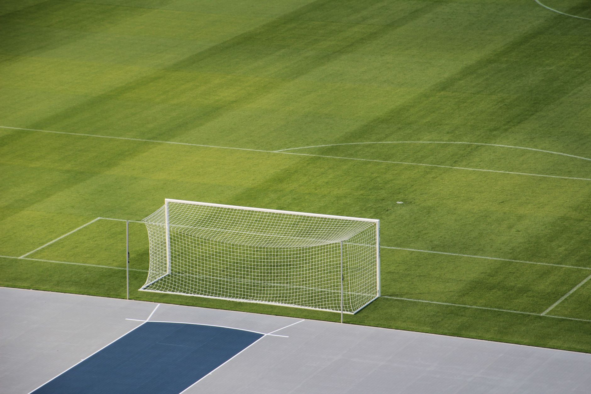 Imagem ilustrativa: Vista aérea de um campo de futebol vazio, mostrando o gol e a grama verde.