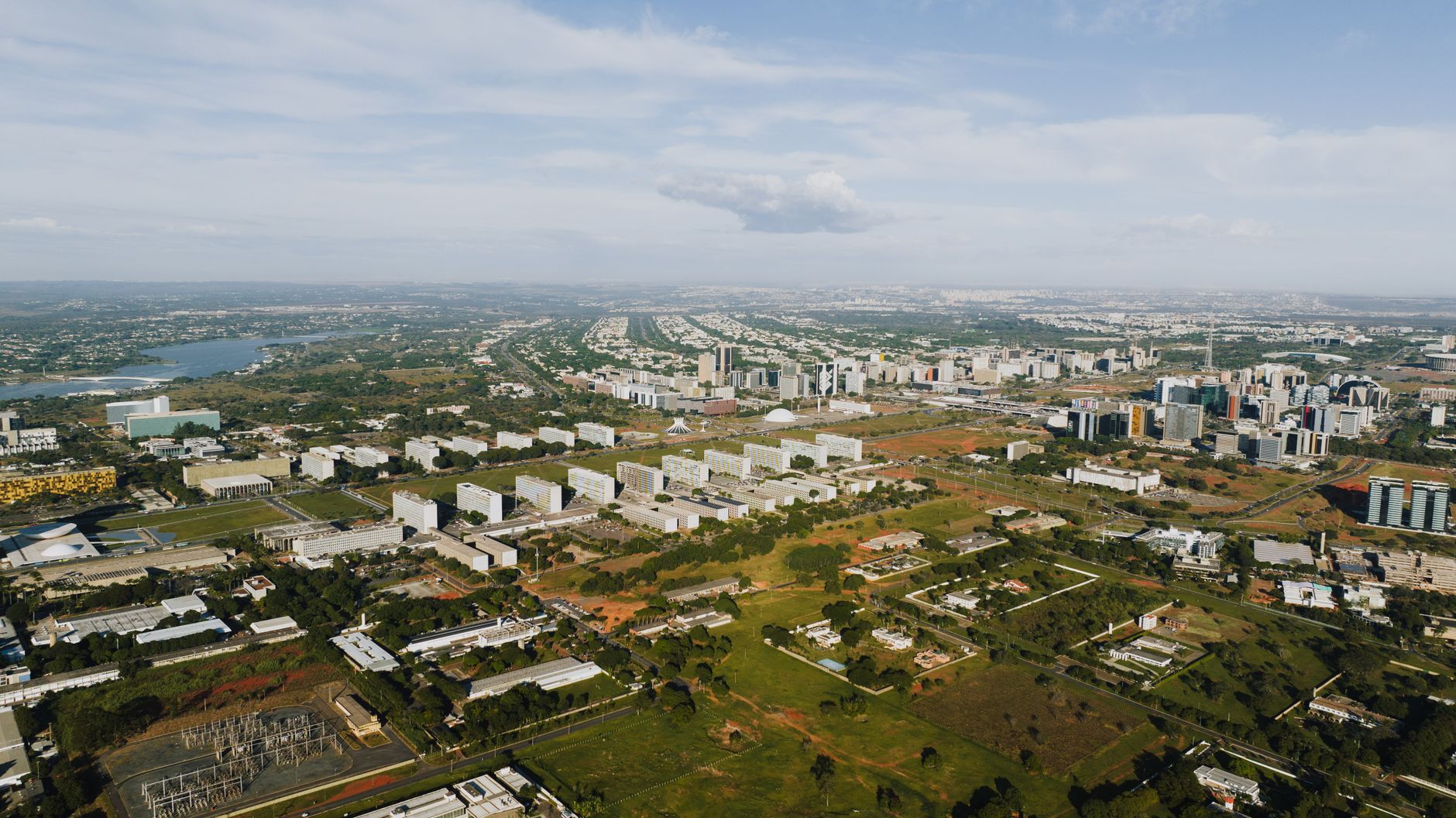 Imagem ilustrativa: Imagem aérea de Brasília mostrando sua paisagem urbana, edifícios e vegetação durante o dia.