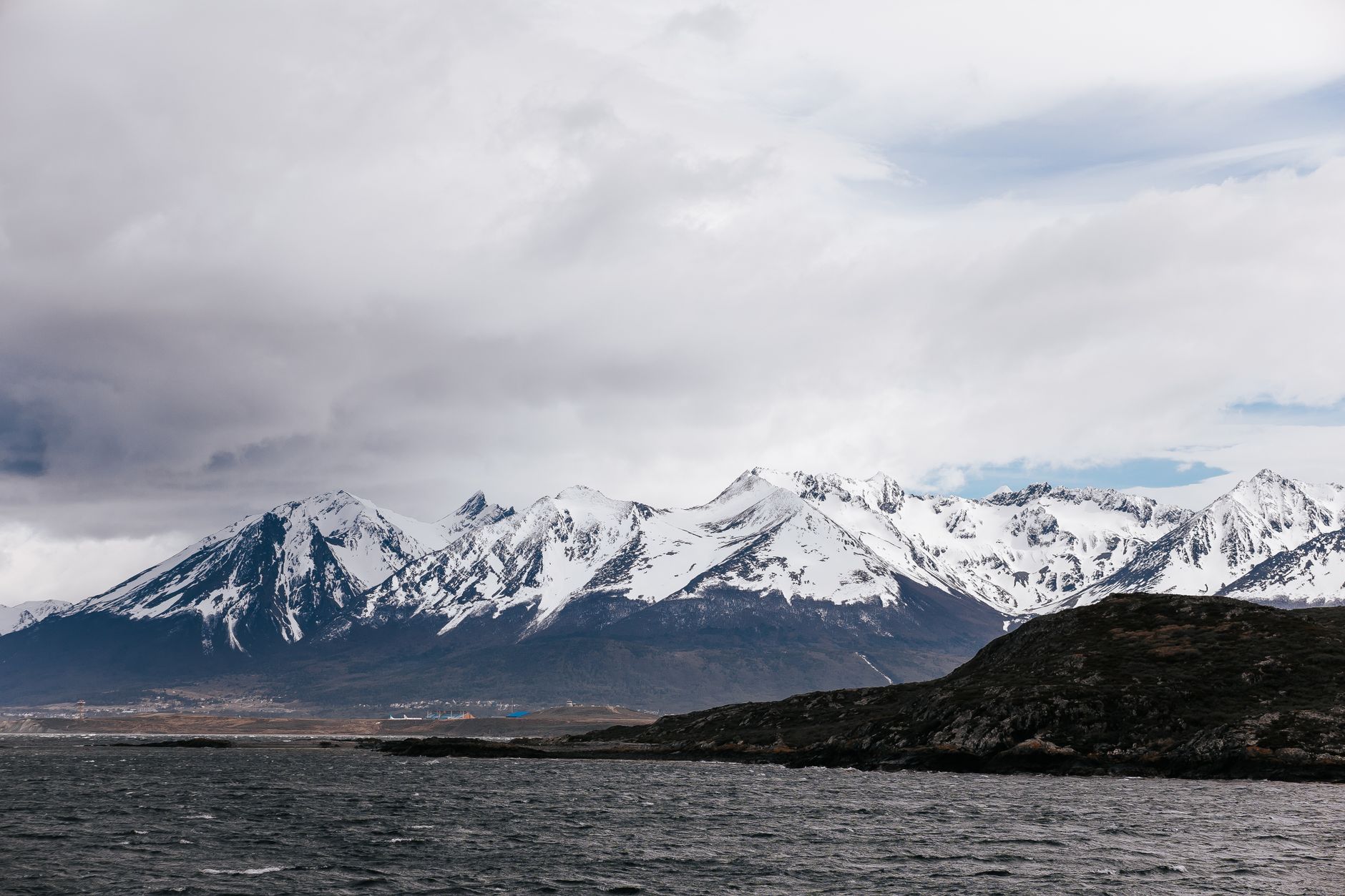 Imagem ilustrativa: Dramáticas montanhas nevadas dos Andes sob céus nublados em Ushuaia, Argentina.
