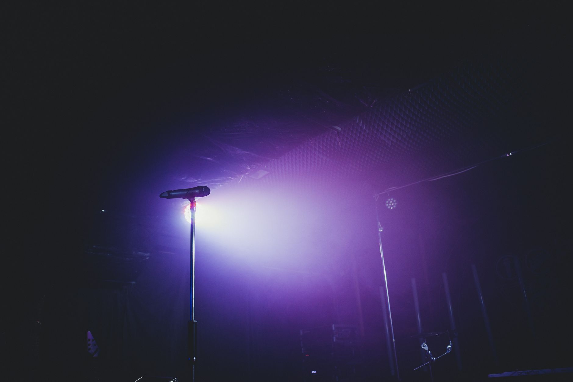 Imagem ilustrativa: Uma configuração de palco envolvente com um microfone sob luz roxa, perfeito para shows.