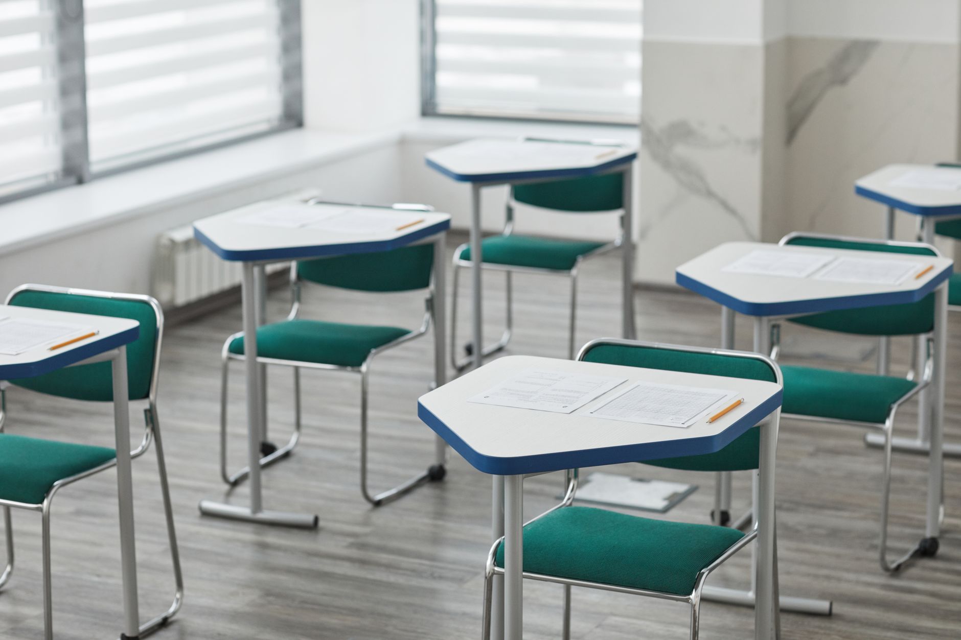 Imagem ilustrativa: Uma sala de aula vazia com mesas organizadas, provas e lápis prontos para os alunos.