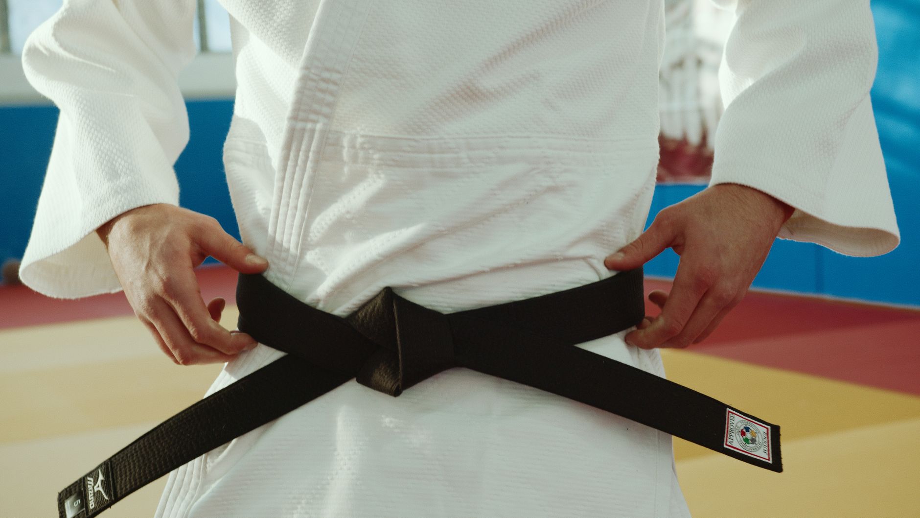 Imagem ilustrativa: Close-up of a martial artist tying a black belt, symbolizing expertise and discipline.