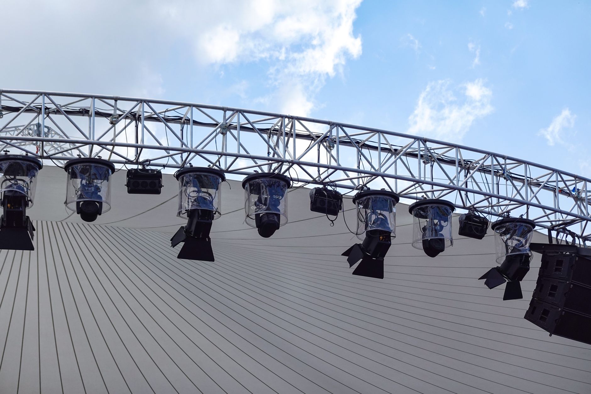 Imagem ilustrativa: Vista de cima de um palco ao ar livre com uma configuração de iluminação moderna contra um céu azul.