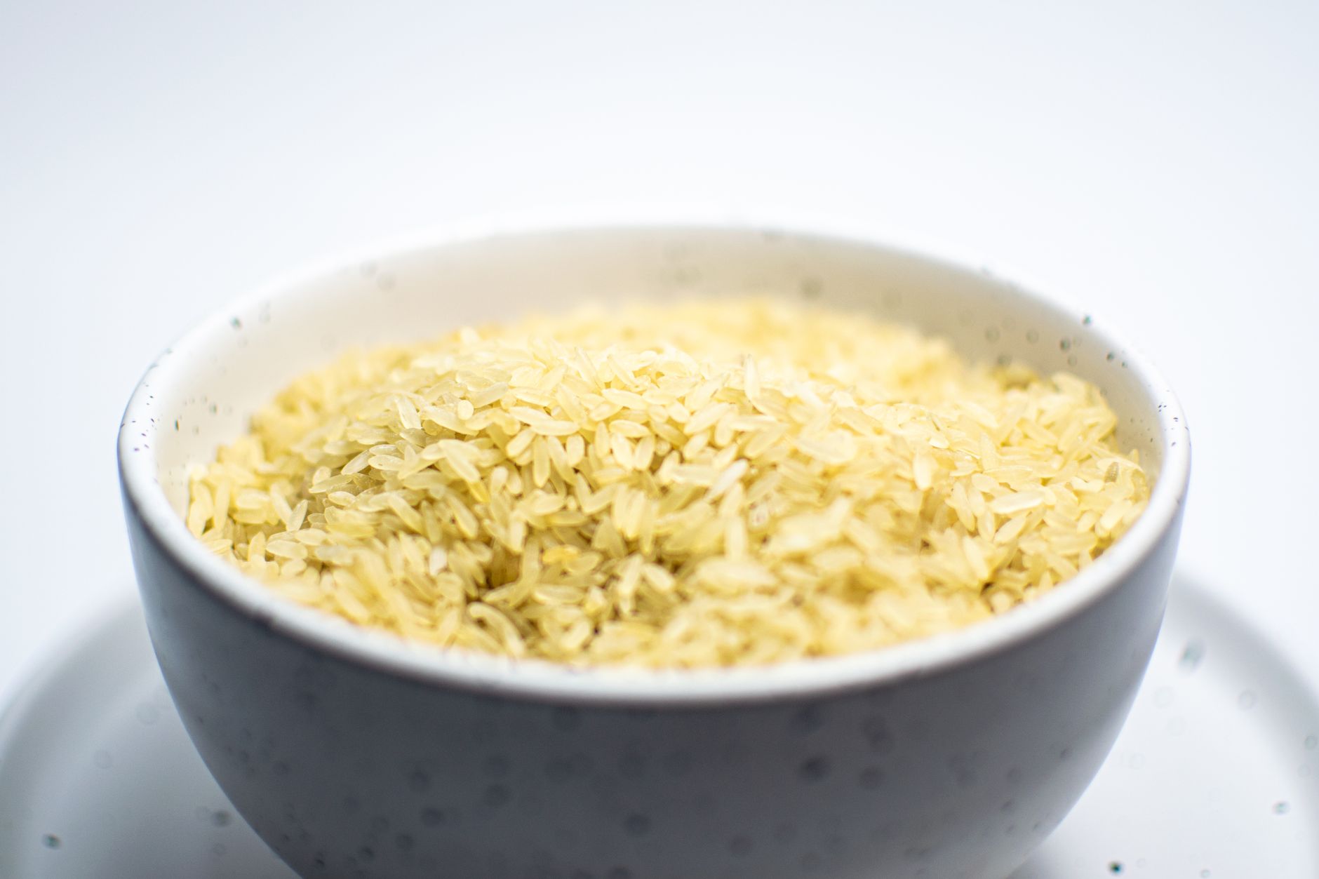 Imagem ilustrativa: Close-up de uma tigela branca cheia de arroz cru, mostrando textura e detalhes.