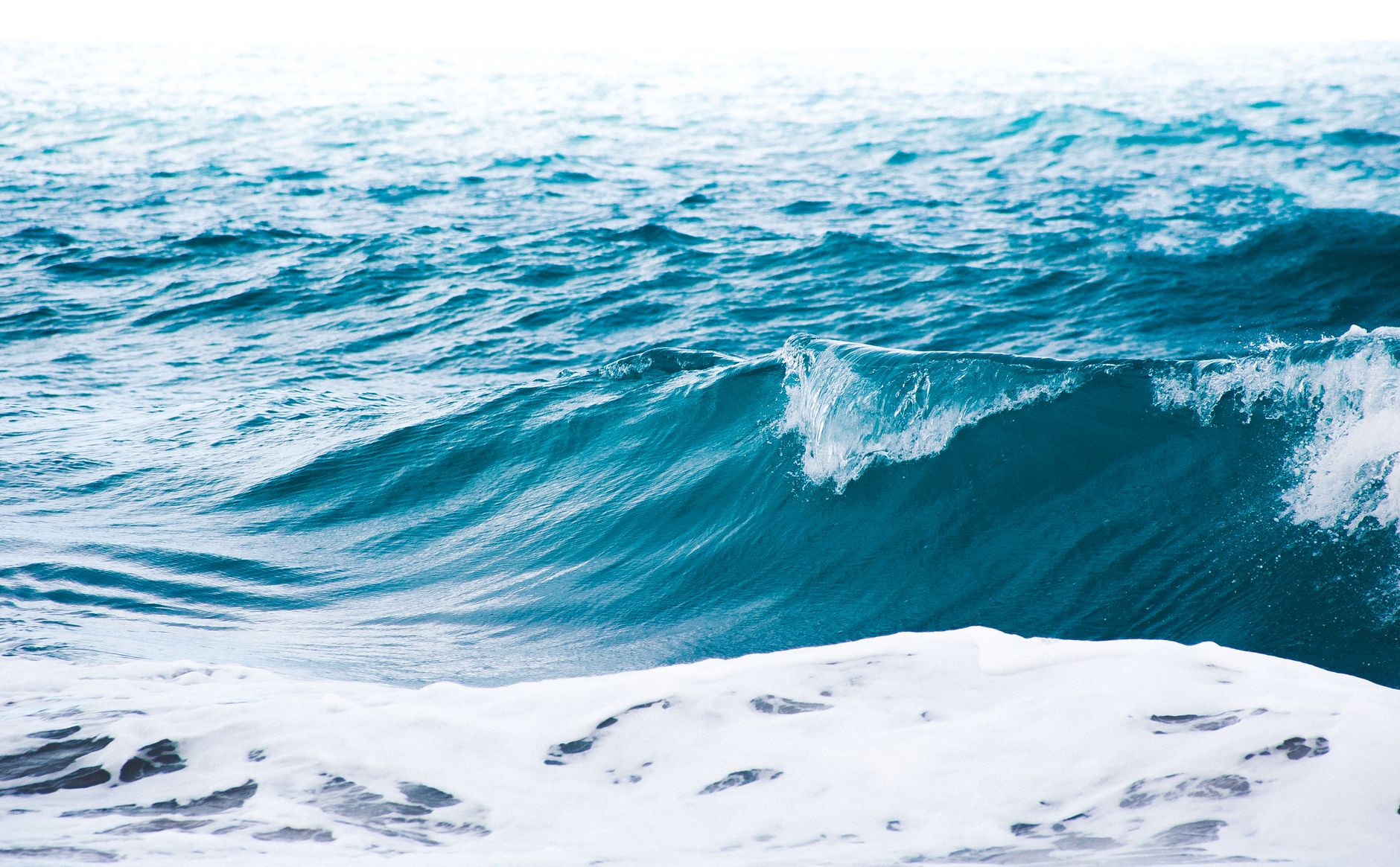 Imagem ilustrativa: Uma vista deslumbrante das ondas do oceano quebrando com tons de azul vibrante na costa do Brasil.